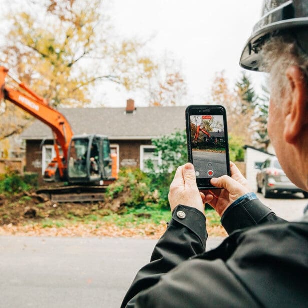 man taking photo of home on smartphone