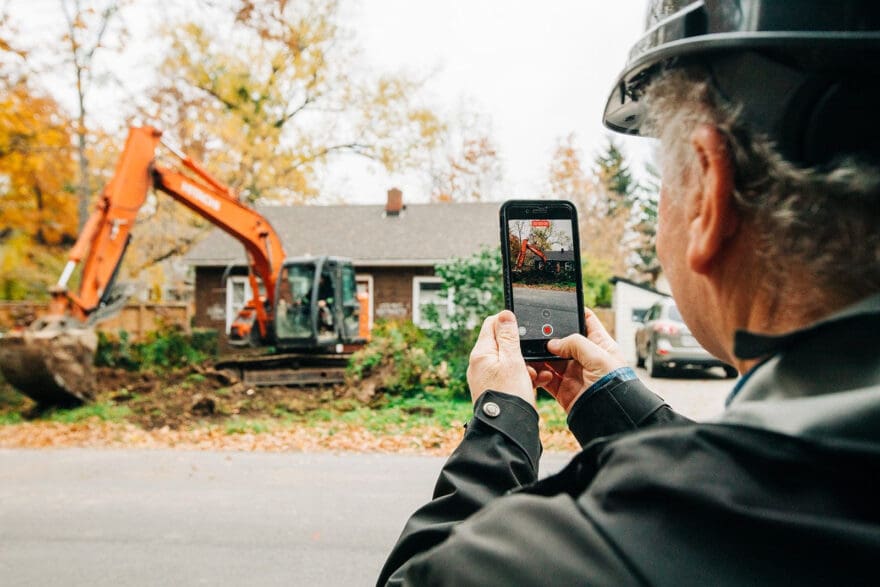 man taking photo of home on smartphone