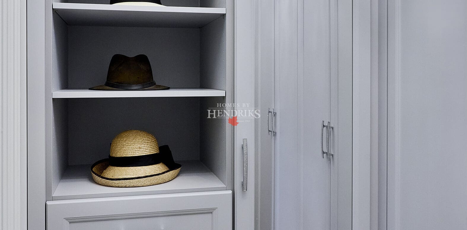 Interior view of a spacious walk-in closet with grey cabinetry, showcasing organized shelving, hanging space, and a stylish layout for easy access to clothing and accessories.