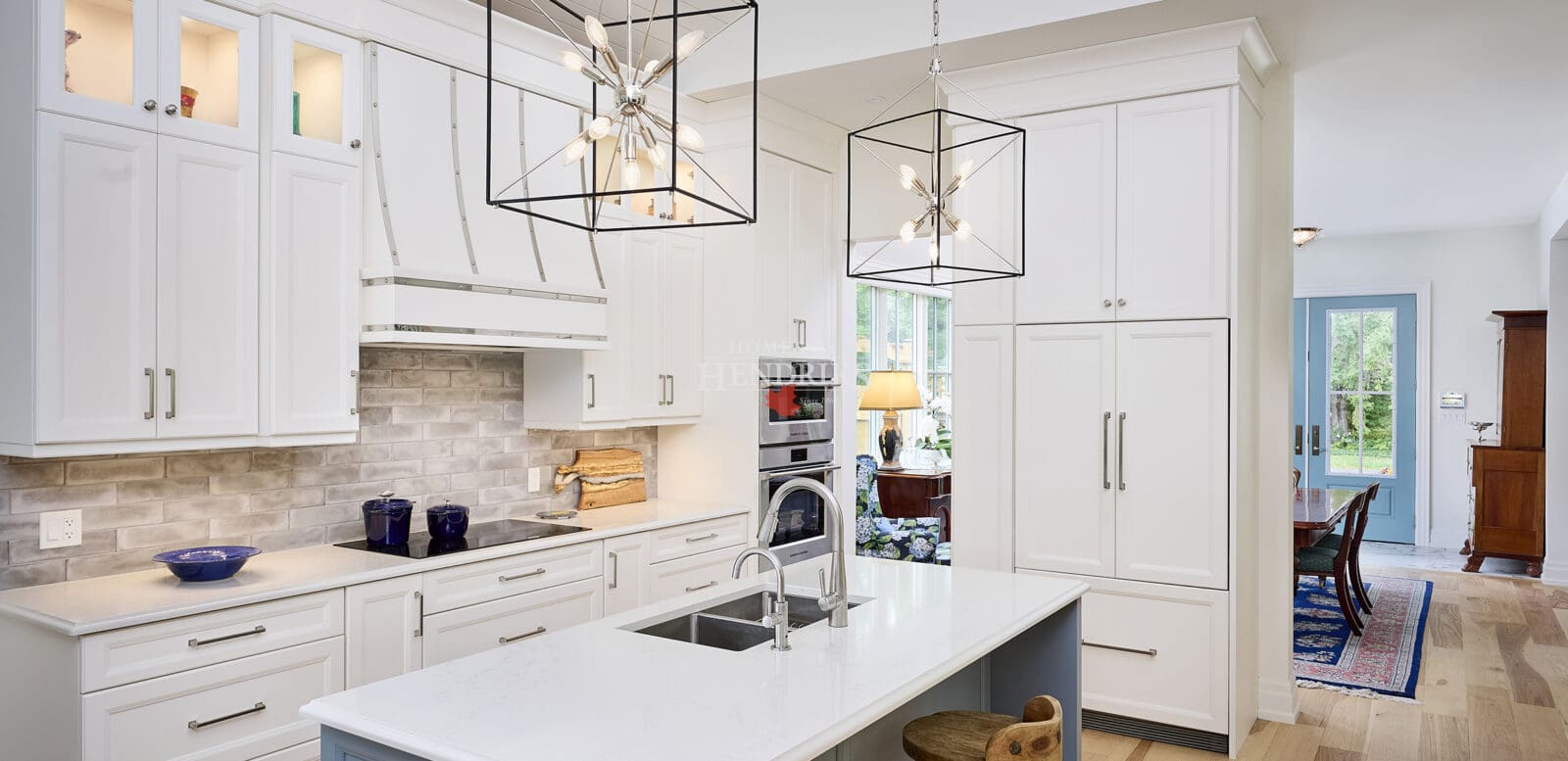 Interior view of a kitchen with white cabinetry, a vaulted ceiling, and hardwood flooring, creating a bright and open space.