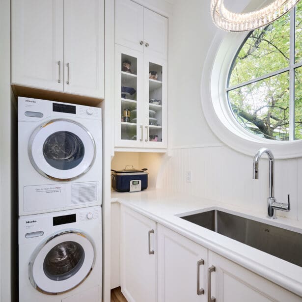 Interior view of a laundry room with modern appliances, white cabinetry, and a functional layout, providing a bright and organized space for chores.