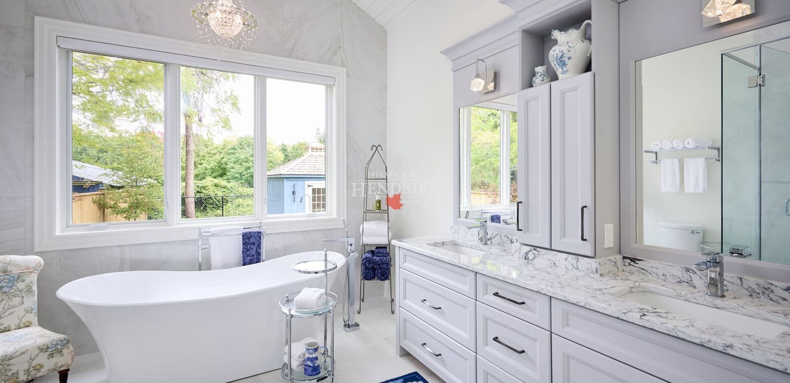 Interior view of a primary ensuite bathroom featuring grey cabinetry, a freestanding soaker tub, and a vaulted ceiling, combining elegance and comfort.