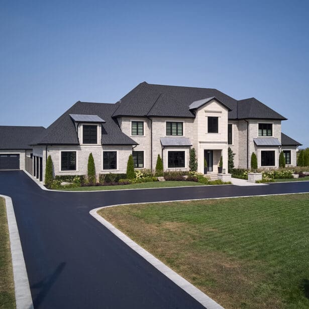 Front entry way on a custom home featuring limestone accents, paved driveway and a beautiful landscape. Chateau Style Home