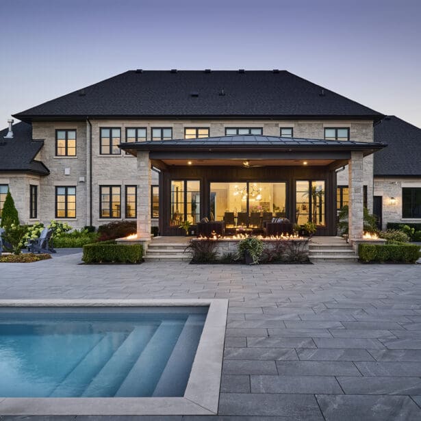 Elegant custom home with a beautiful stone exterior, limestone accents, and a stunning pool area surrounded by lush landscaping.